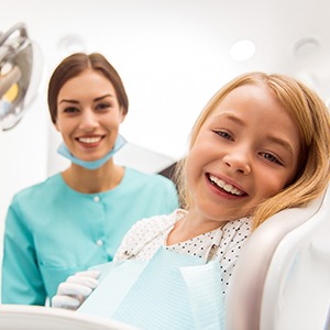 A young girl and her dental hygienist smile after receiving a fluoride treatment