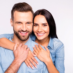A young man and woman wearing denim shirts, hugging and smiling after having direct bonding procedures