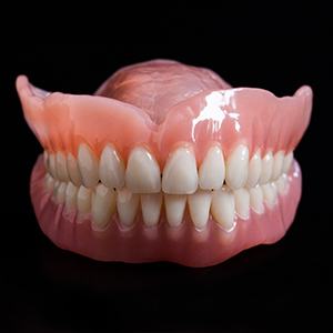 An up-close view of a top and bottom denture taking the shape of a person’s smile