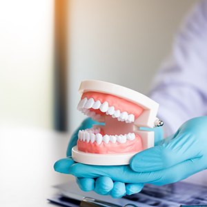 East Islip dentist holding model of teeth over X-ray