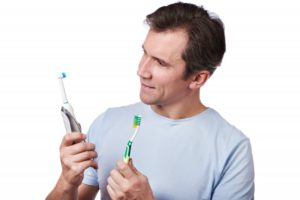 man choosing between electric and manual toothbrush