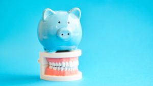 piggy bank atop model teeth representing cost of sedation dentistry